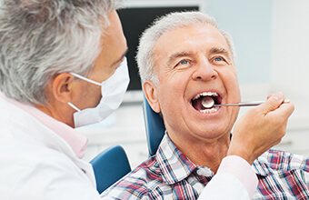 Older male patient examined by dentist