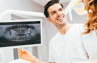 Dentist and patient examine digital x-rays