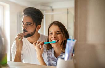 Couple preventing dental emergencies in Houston by brushing