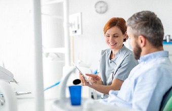 Dental assistant showing patient information on tablet