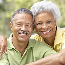 Older couple with dental implants in Houston smiling outside