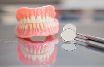 dentures in Houston sitting next to dental mirrors