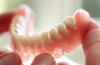 Hands holding a full denture restoration