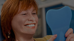 Female patient viewing smile in handheld mirror