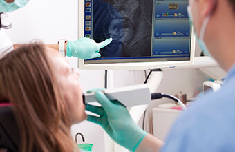 Woman and dentist examining smile photos on chairside monitor