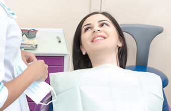 Female patient in dental chair smiling at dentist