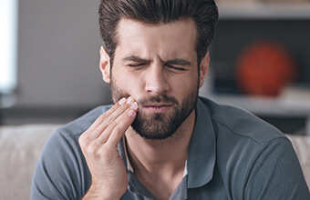 Man grimacing and holding jaw