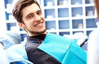 young man smiling sitting in dentist chair