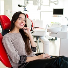 Woman sitting in patient’s chair and smiling brightly