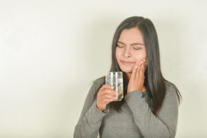 Woman with sensitive teeth holding glass of water