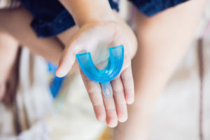 Houston emergency dentist holding out a custom-made sports mouthguard