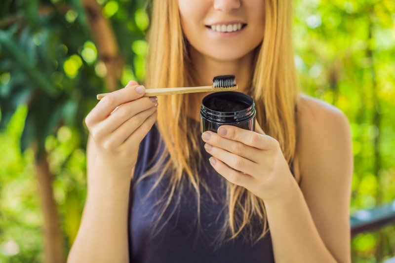Woman holding toothbrush with activated charcoal toothpaste