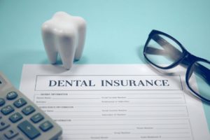 Molar, glasses, calculator, and dental insurance form