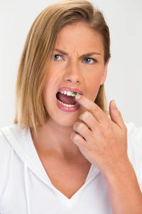 Woman picking at her teeth to remove object